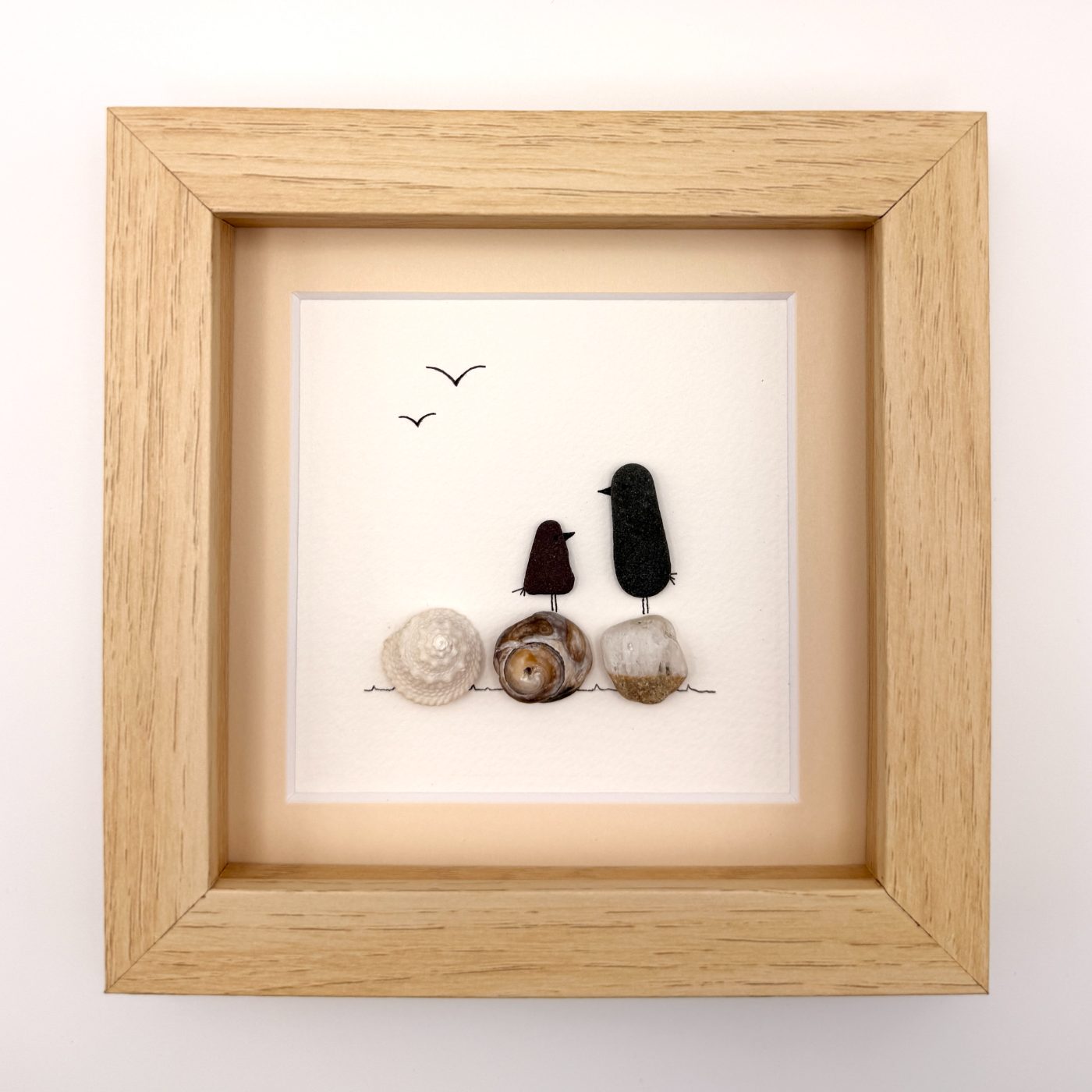 Two dark sea glass birds on shells