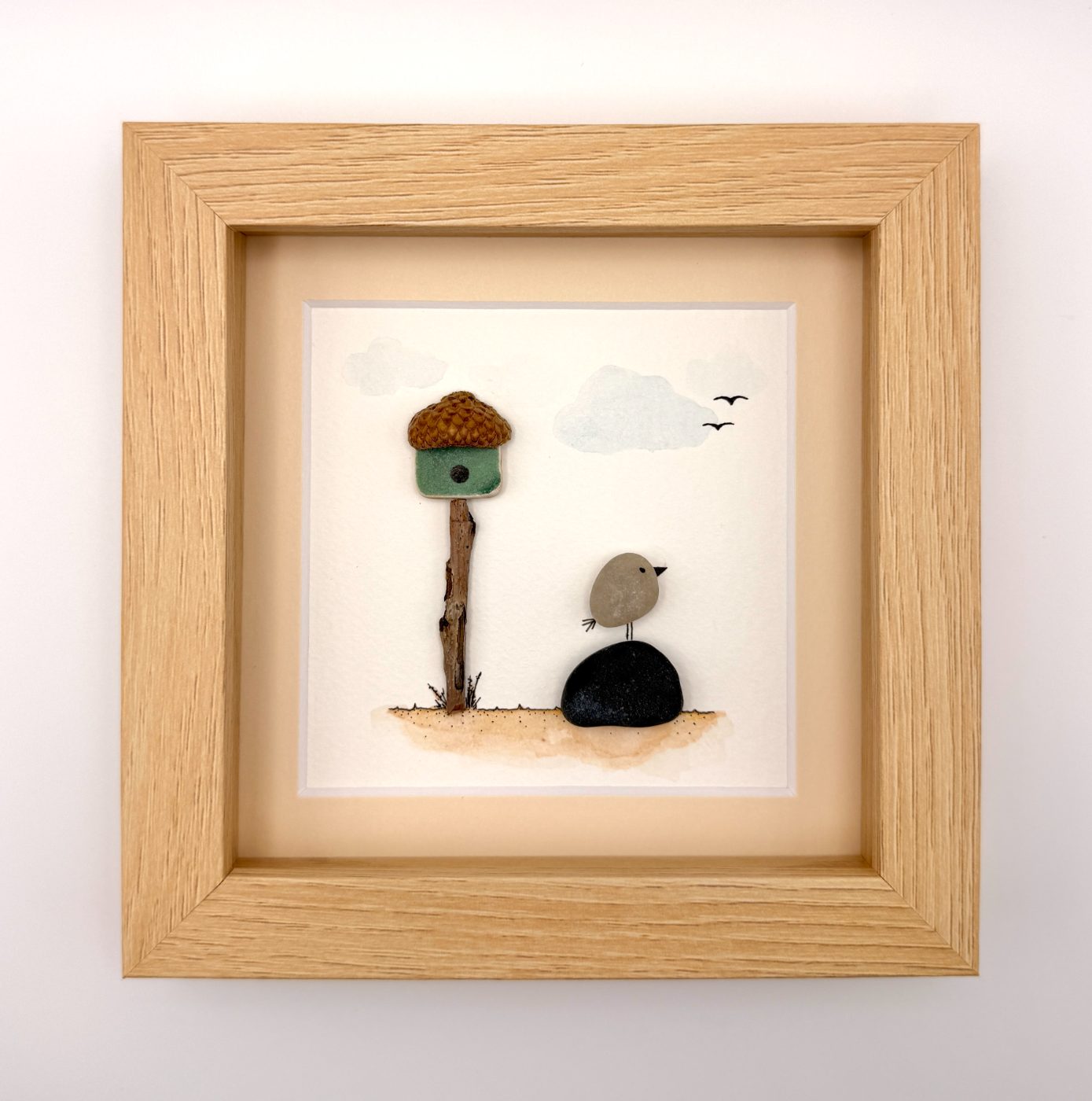 Pebble bird beside an acorn birdhouse